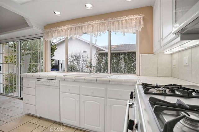 kitchen with stainless steel gas stove, tile countertops, dishwasher, and a sink