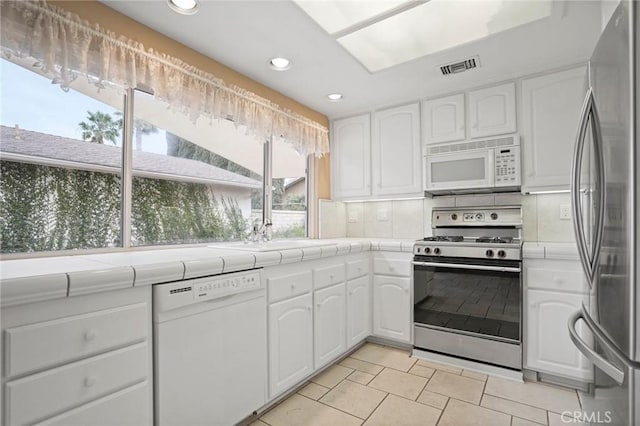 kitchen featuring white appliances, tile countertops, and white cabinets