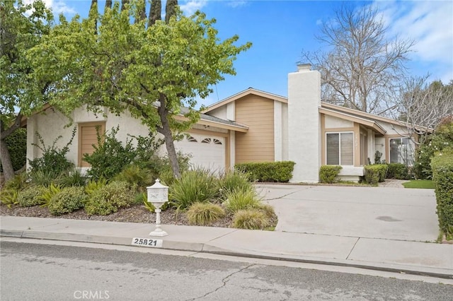 mid-century home with stucco siding, a garage, driveway, and a chimney