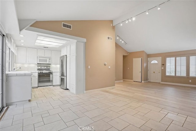 kitchen with visible vents, open floor plan, stainless steel appliances, white cabinets, and tile counters