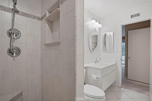 full bathroom featuring tile patterned flooring, visible vents, toilet, tiled shower, and vanity