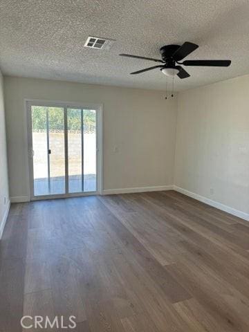 empty room featuring visible vents, ceiling fan, baseboards, and wood finished floors