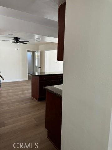 kitchen featuring dark countertops, baseboards, a ceiling fan, and wood finished floors