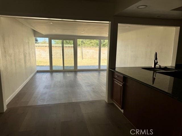 interior space with dark countertops, wood finished floors, baseboards, and a sink