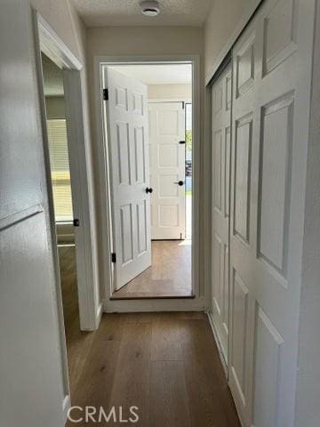 corridor with a textured ceiling and wood finished floors