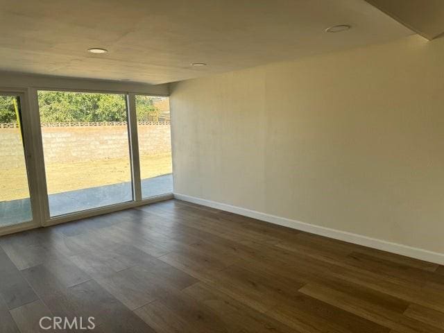 empty room featuring baseboards and dark wood-type flooring