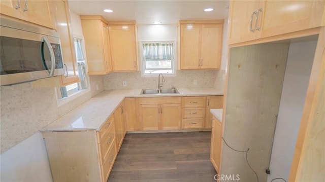 kitchen featuring light brown cabinetry, stainless steel microwave, and a sink