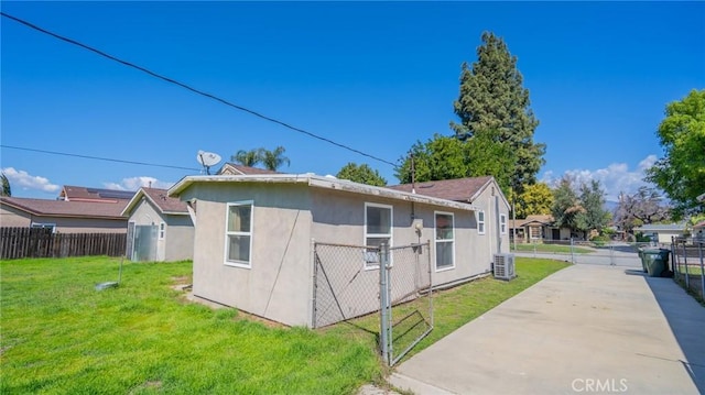 view of side of property featuring central air condition unit, a yard, fence, and stucco siding