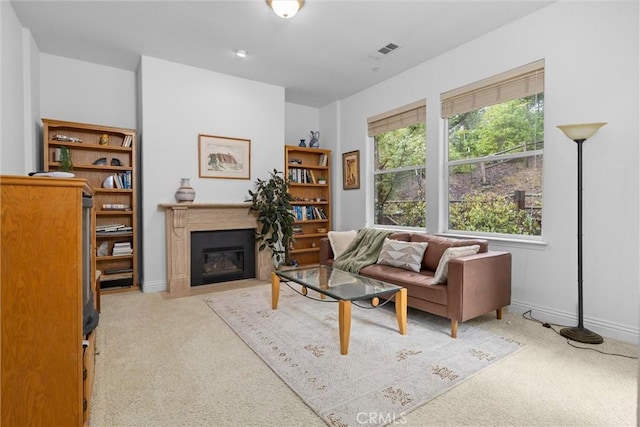 carpeted living area with a fireplace with flush hearth, a wealth of natural light, visible vents, and baseboards