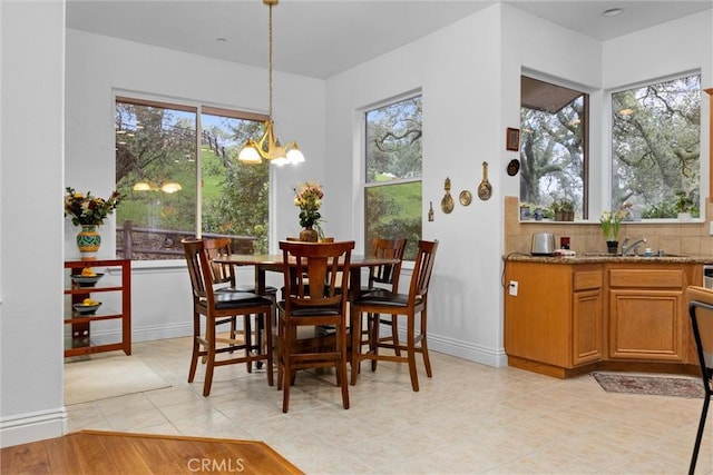dining space with baseboards, a wealth of natural light, a notable chandelier, and light tile patterned flooring