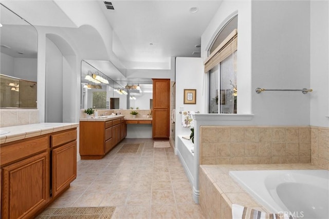 bathroom featuring two vanities, tiled shower, visible vents, tile patterned flooring, and a garden tub