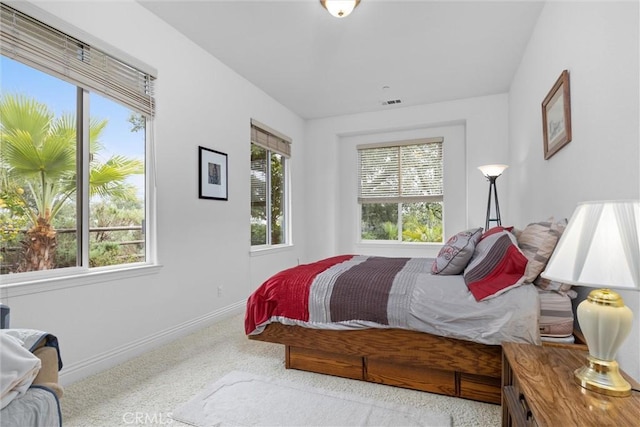 carpeted bedroom featuring visible vents, baseboards, and multiple windows