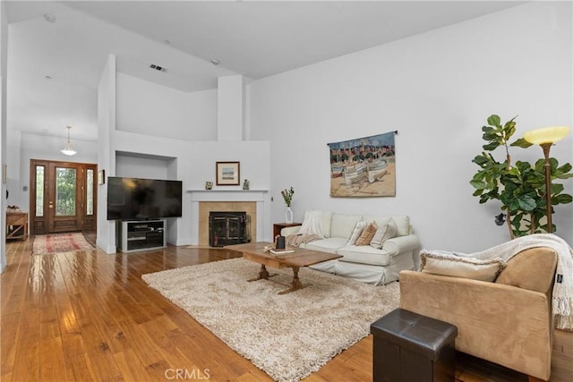 living room with hardwood / wood-style floors, a tiled fireplace, and visible vents