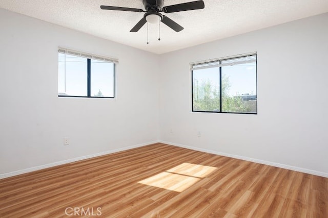 unfurnished room with baseboards, a textured ceiling, and light wood-style flooring