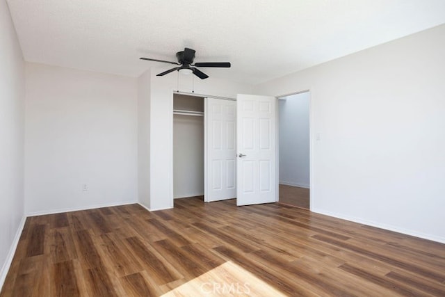 unfurnished bedroom with ceiling fan, wood finished floors, a closet, and baseboards