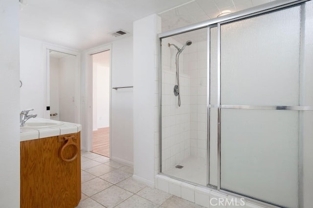 bathroom with tile patterned flooring, visible vents, a stall shower, and vanity