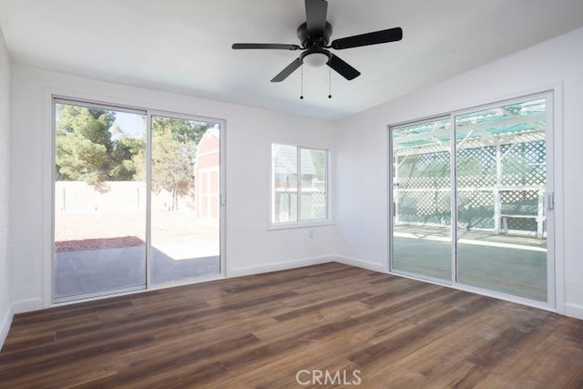 unfurnished room featuring baseboards, dark wood finished floors, and a ceiling fan