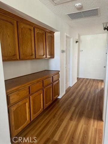 hall with dark wood-style floors, visible vents, and a textured ceiling