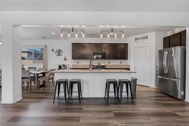 kitchen with a kitchen breakfast bar, dark brown cabinets, and stainless steel appliances