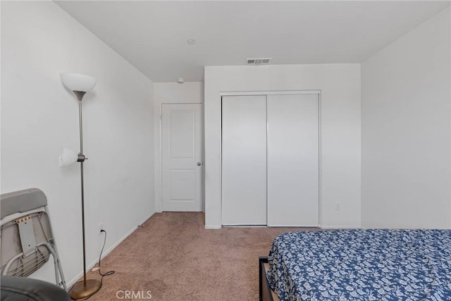 carpeted bedroom with baseboards, visible vents, and a closet