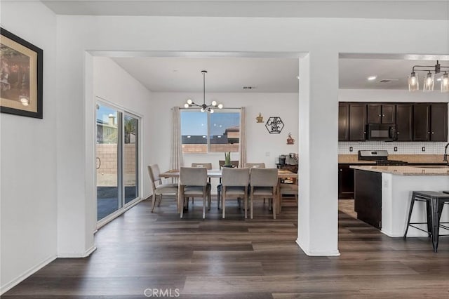 dining space featuring baseboards, a notable chandelier, and dark wood-style floors