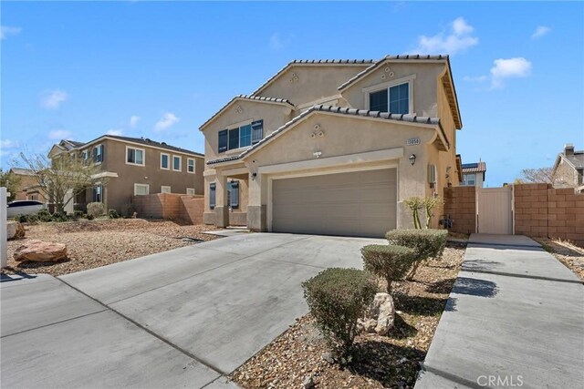 view of front facade featuring stucco siding, concrete driveway, fence, and a gate