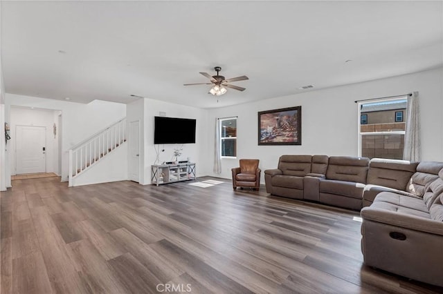 living area with ceiling fan, visible vents, wood finished floors, and stairway