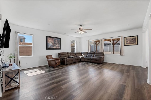 living room featuring baseboards, a ceiling fan, and dark wood-style flooring