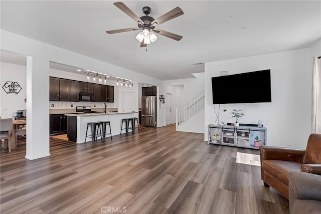 living room with stairway, wood finished floors, visible vents, and ceiling fan