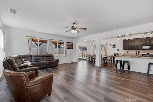 living room featuring visible vents, dark wood-type flooring, and ceiling fan