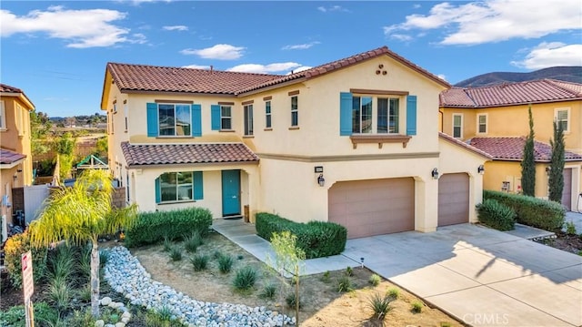 mediterranean / spanish-style house featuring a tile roof, concrete driveway, a garage, and stucco siding