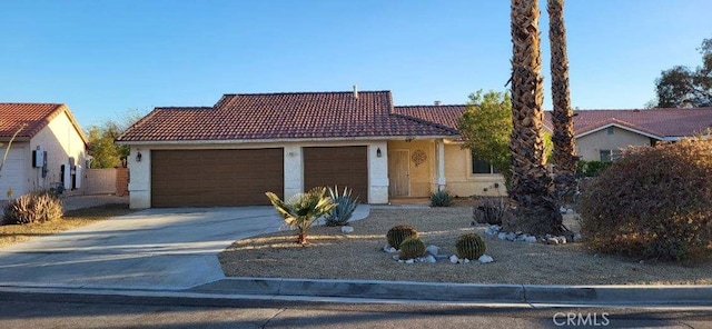 view of front of home featuring stucco siding, driveway, a tile roof, and a garage