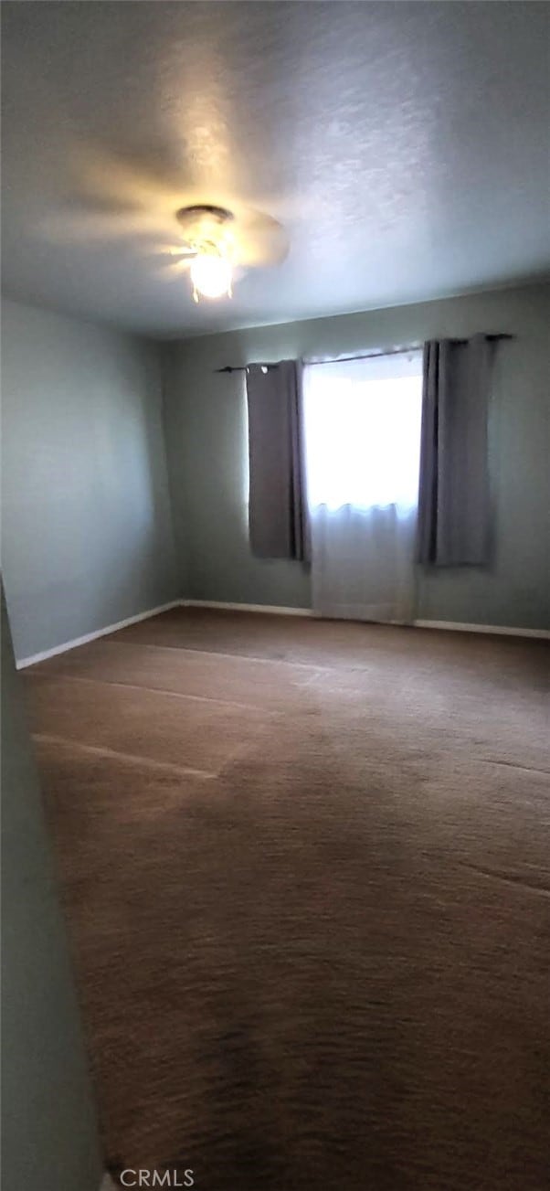 empty room featuring baseboards and carpet