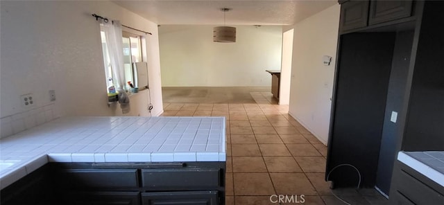 interior space with tile patterned floors, tile counters, and hanging light fixtures