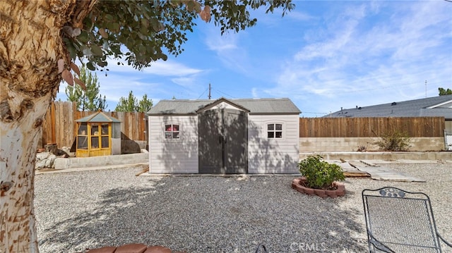 rear view of house with an outbuilding, a storage unit, and a fenced backyard