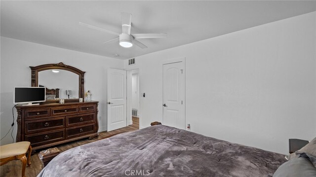 bedroom with ceiling fan, visible vents, and wood finished floors