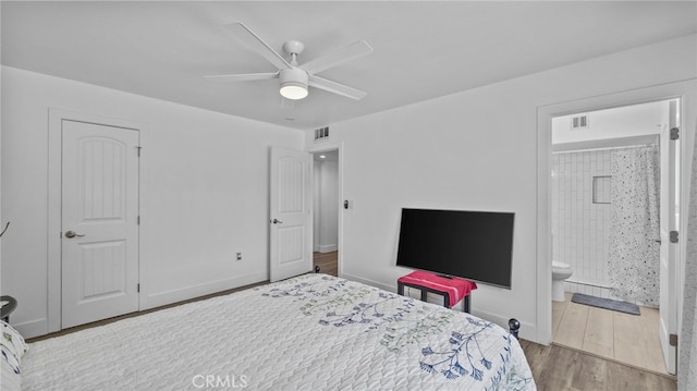 bedroom featuring wood finished floors, visible vents, ensuite bathroom, and baseboards