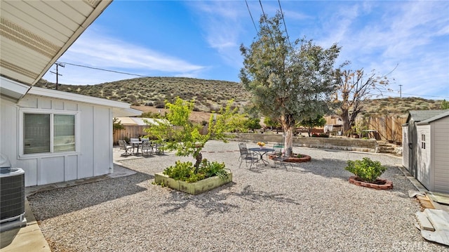 view of yard with central AC unit, a fenced backyard, an outdoor structure, a storage unit, and a patio