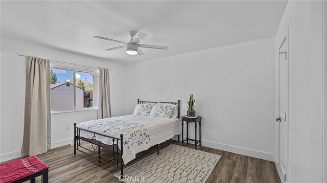 bedroom featuring baseboards, wood finished floors, and a ceiling fan