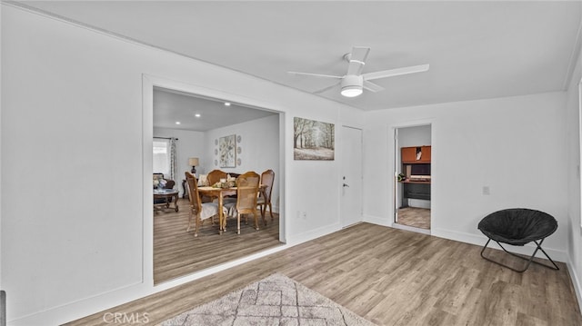 living area featuring baseboards, ceiling fan, and wood finished floors