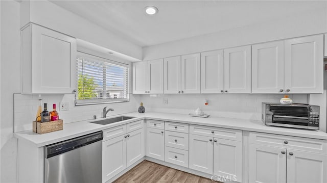 kitchen featuring a sink, stainless steel dishwasher, white cabinets, and light countertops