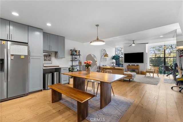 kitchen with gray cabinets, arched walkways, stainless steel refrigerator with ice dispenser, and light wood finished floors