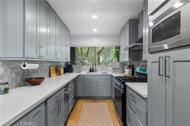 kitchen featuring a sink, backsplash, appliances with stainless steel finishes, and gray cabinetry