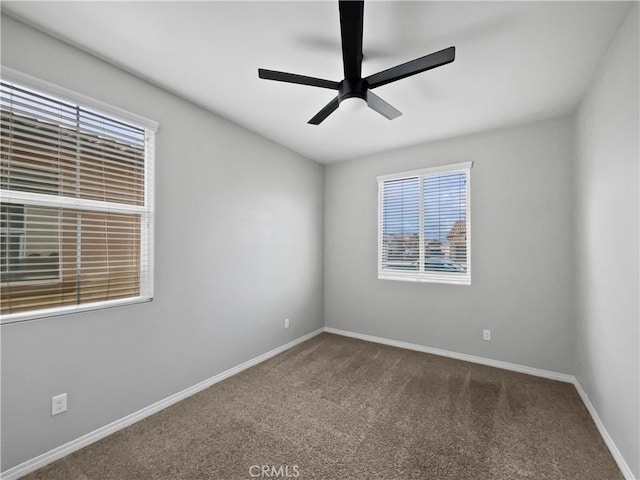 carpeted spare room featuring ceiling fan and baseboards