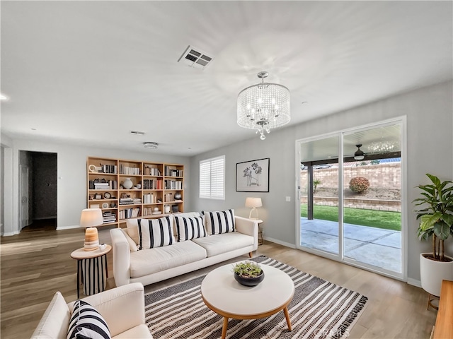 living area featuring visible vents, baseboards, a notable chandelier, and wood finished floors