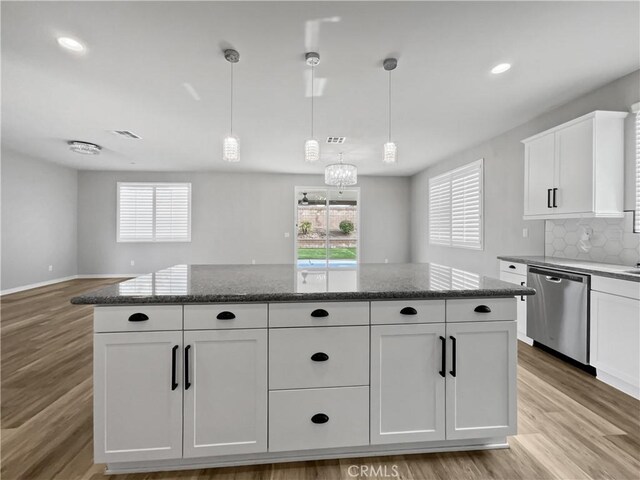 kitchen featuring white cabinetry, light wood finished floors, decorative backsplash, stainless steel dishwasher, and a center island