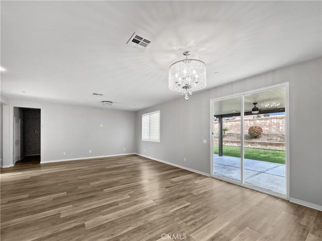 empty room featuring wood finished floors, visible vents, and baseboards