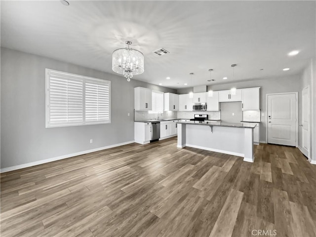 kitchen with dark countertops, visible vents, dark wood-type flooring, appliances with stainless steel finishes, and white cabinets