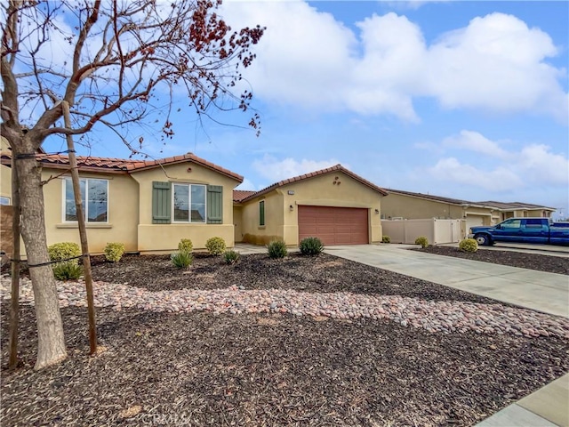 mediterranean / spanish-style house with fence, a tile roof, concrete driveway, stucco siding, and a garage