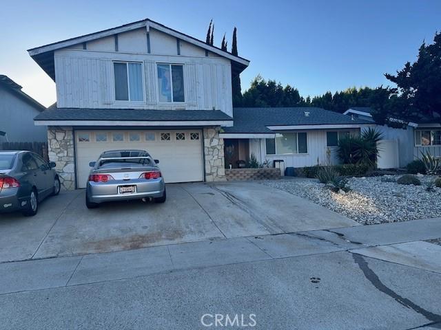 traditional home with stone siding, an attached garage, and driveway